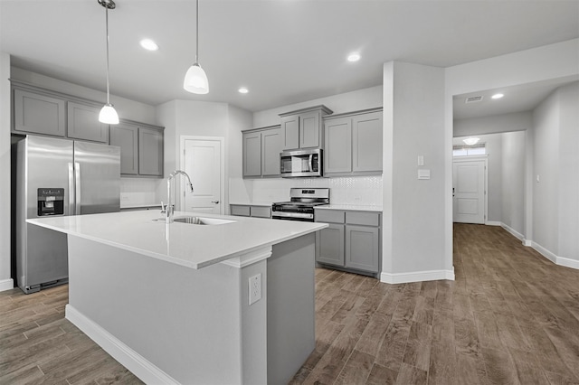 kitchen with gray cabinets, decorative backsplash, stainless steel appliances, and light wood-type flooring