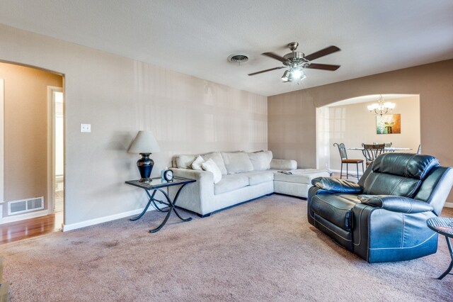 living room with ceiling fan with notable chandelier, a textured ceiling, and carpet floors