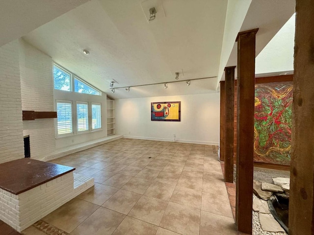 unfurnished living room with built in features, light tile patterned flooring, track lighting, and lofted ceiling