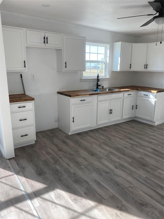 kitchen with dark hardwood / wood-style floors, wood counters, white cabinetry, sink, and ceiling fan