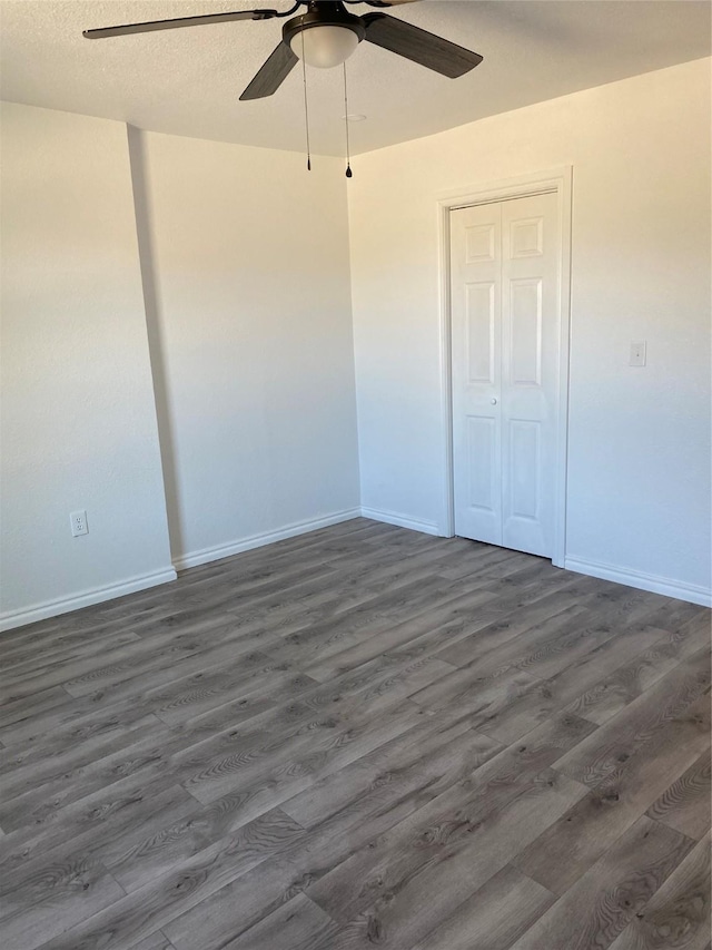 unfurnished bedroom featuring ceiling fan, a textured ceiling, dark hardwood / wood-style flooring, and a closet