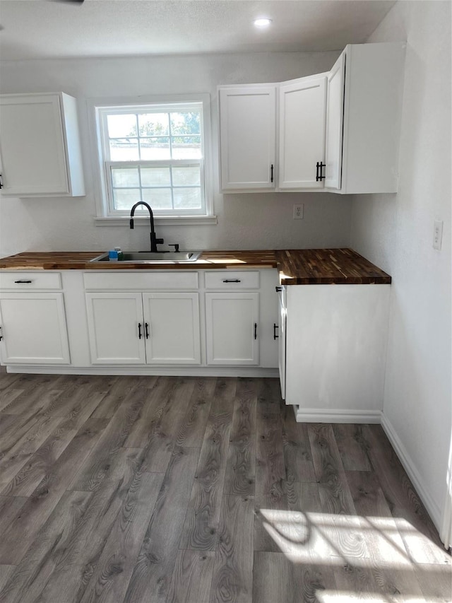 kitchen with white cabinetry, dark hardwood / wood-style flooring, butcher block counters, and sink