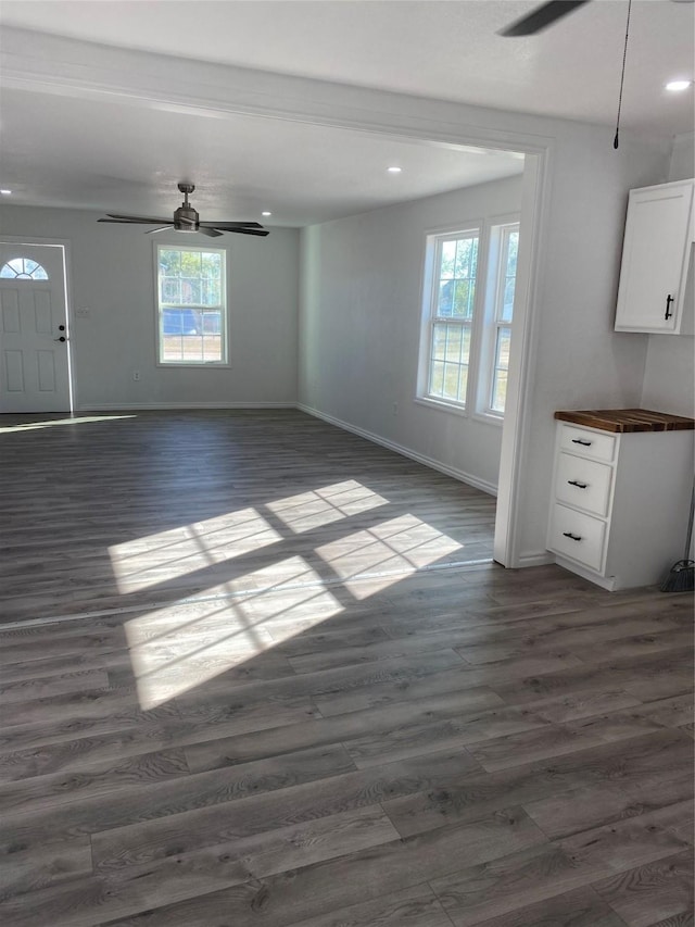 unfurnished living room with dark wood-type flooring and ceiling fan