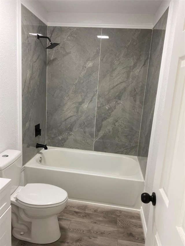 full bathroom with hardwood / wood-style flooring, tiled shower / bath, vanity, and toilet