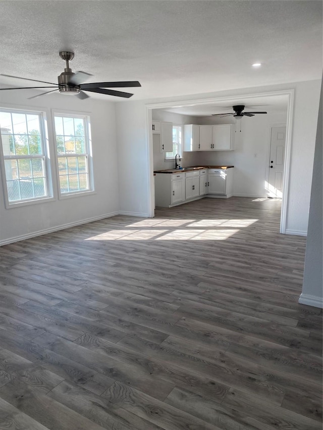 unfurnished living room featuring ceiling fan, dark hardwood / wood-style flooring, sink, and a textured ceiling