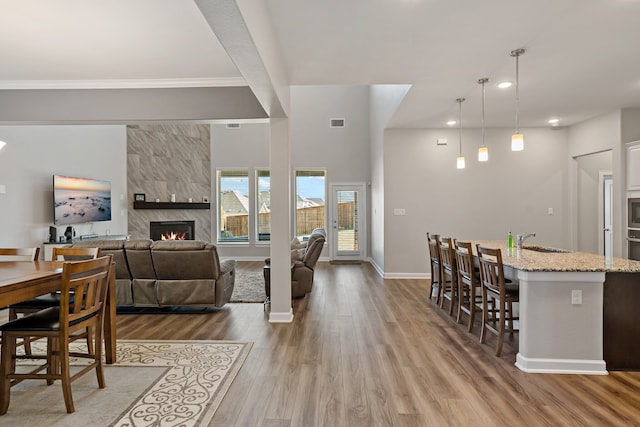 living room with ornamental molding, hardwood / wood-style flooring, sink, and a tile fireplace