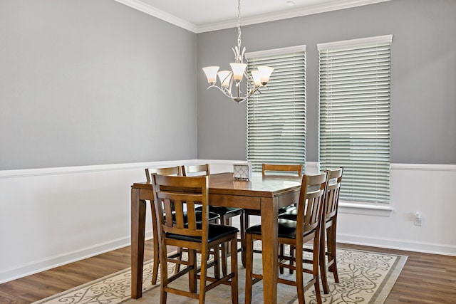 dining area featuring ornamental molding, wood-type flooring, and an inviting chandelier