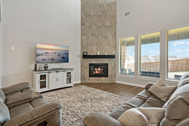 living room with hardwood / wood-style floors, a fireplace, and a towering ceiling