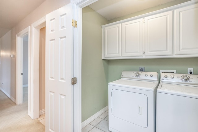 laundry area featuring independent washer and dryer, cabinets, and light tile patterned flooring