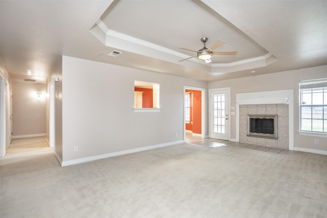 unfurnished living room with light carpet, a fireplace, and a tray ceiling