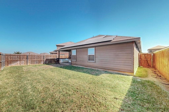 back of property with solar panels, a yard, and a patio area