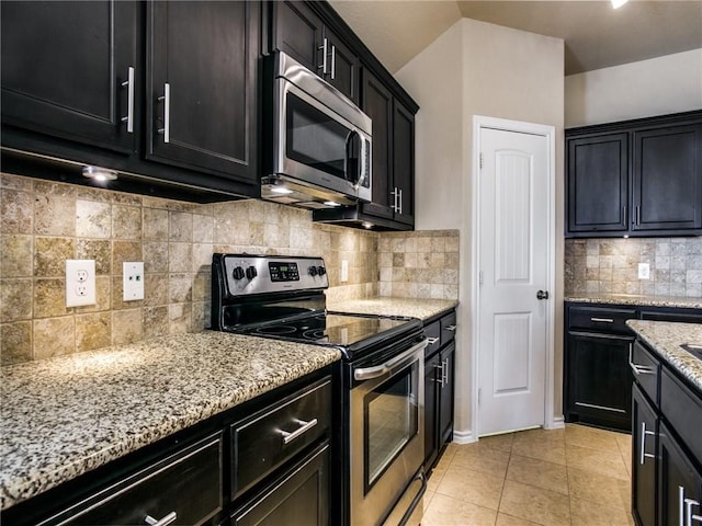 kitchen with light stone countertops, appliances with stainless steel finishes, tasteful backsplash, and light tile patterned floors