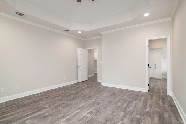 unfurnished bedroom featuring dark hardwood / wood-style floors, a raised ceiling, and crown molding