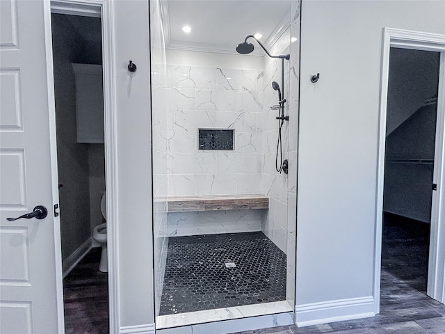 bathroom featuring hardwood / wood-style floors, a tile shower, toilet, and crown molding