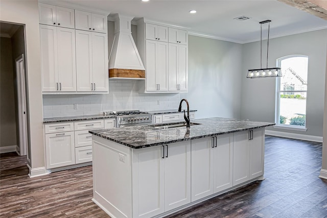 kitchen featuring white cabinets, custom range hood, crown molding, and a kitchen island with sink