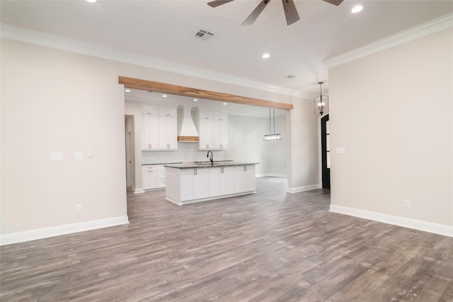 unfurnished living room featuring hardwood / wood-style flooring, ceiling fan, ornamental molding, and sink