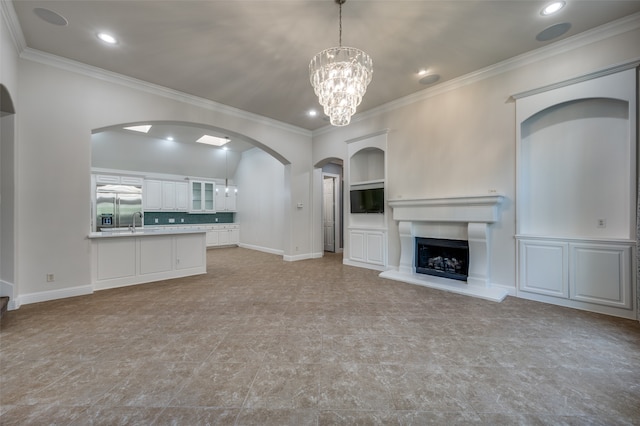 unfurnished living room featuring a chandelier, sink, and crown molding