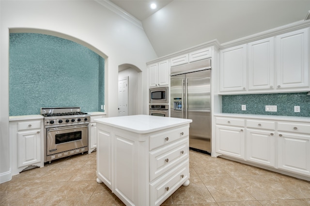 kitchen featuring lofted ceiling, a center island, built in appliances, ornamental molding, and white cabinetry