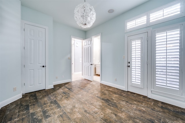 foyer entrance with an inviting chandelier and dark hardwood / wood-style flooring