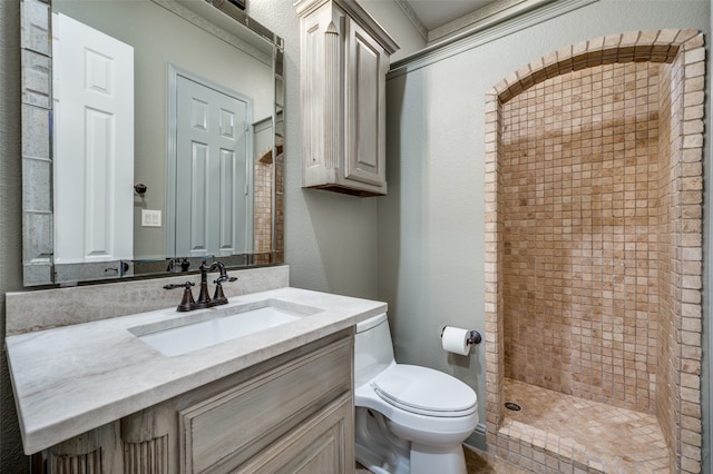 bathroom featuring toilet, vanity, and a tile shower