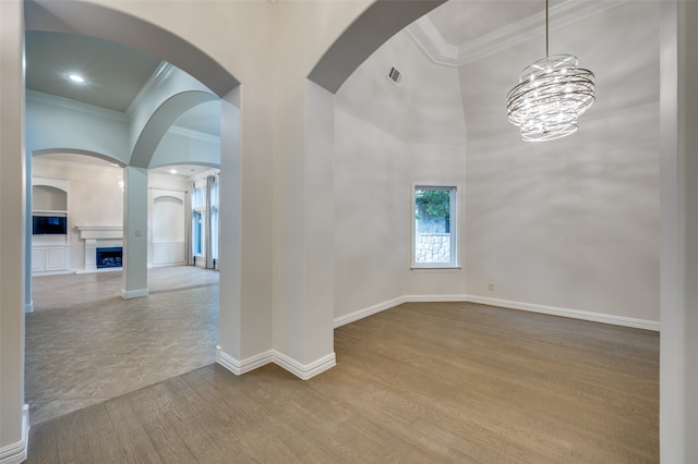 unfurnished room with light wood-type flooring, crown molding, and a notable chandelier