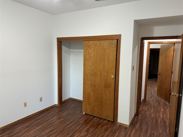 unfurnished bedroom featuring dark wood-type flooring, a textured ceiling, and a closet