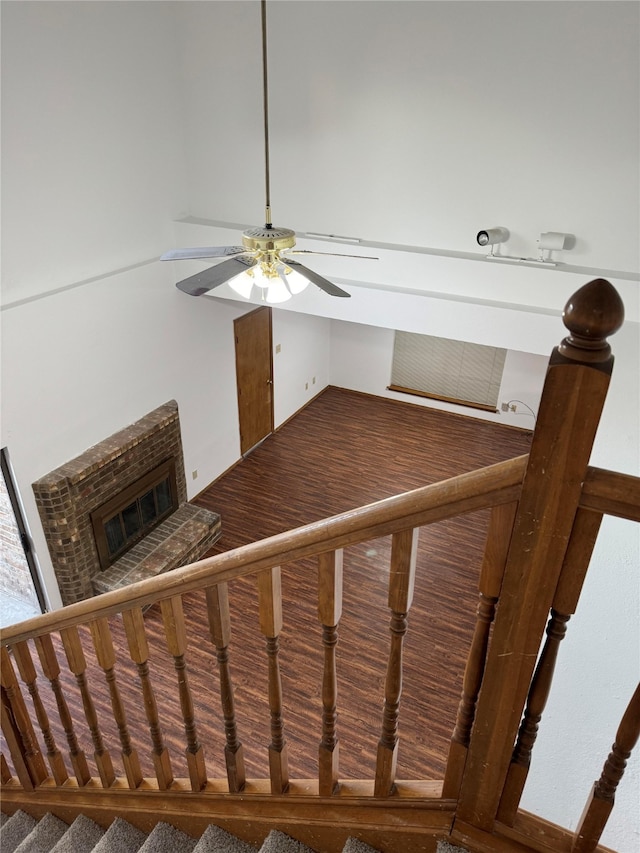 stairway with a fireplace and ceiling fan