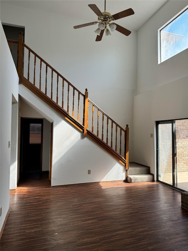 unfurnished living room featuring ceiling fan, high vaulted ceiling, dark hardwood / wood-style flooring, and plenty of natural light