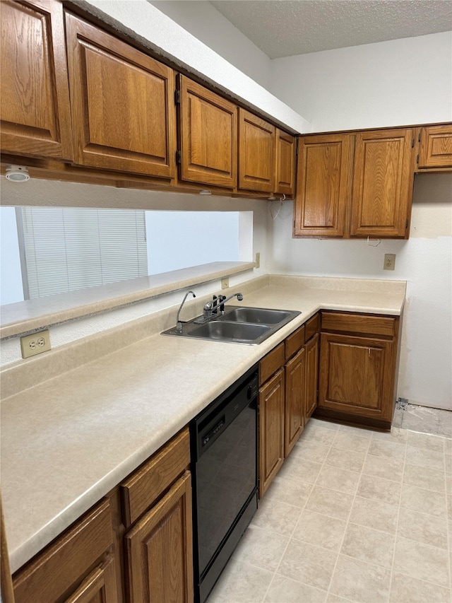 kitchen featuring sink, dishwasher, a textured ceiling, and light tile patterned floors