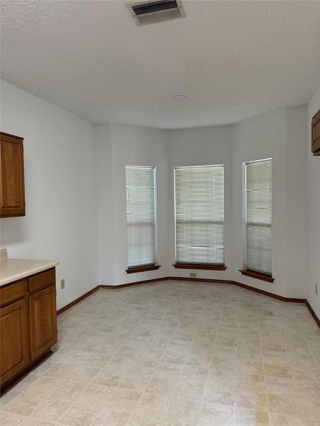 unfurnished dining area featuring a textured ceiling