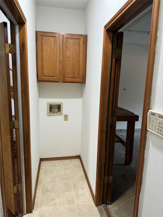 laundry room with hookup for a washing machine, light tile patterned floors, and cabinets