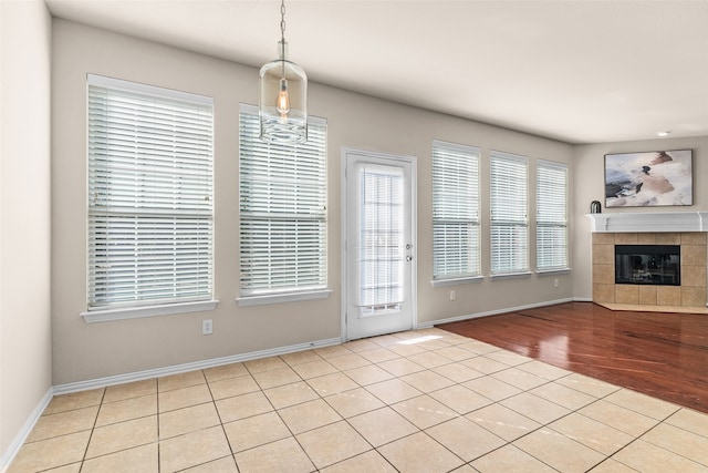 interior space featuring light hardwood / wood-style flooring, a notable chandelier, a wealth of natural light, and a tile fireplace