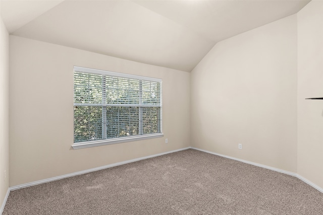 carpeted spare room with vaulted ceiling