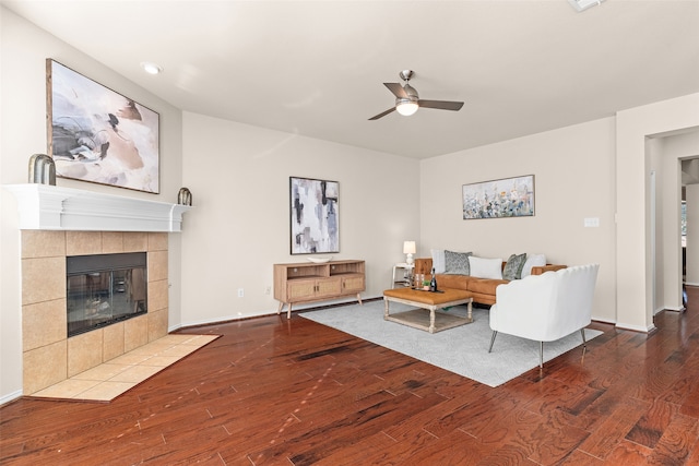 living room featuring a tiled fireplace, wood-type flooring, and ceiling fan