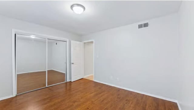 unfurnished bedroom with hardwood / wood-style flooring and a closet