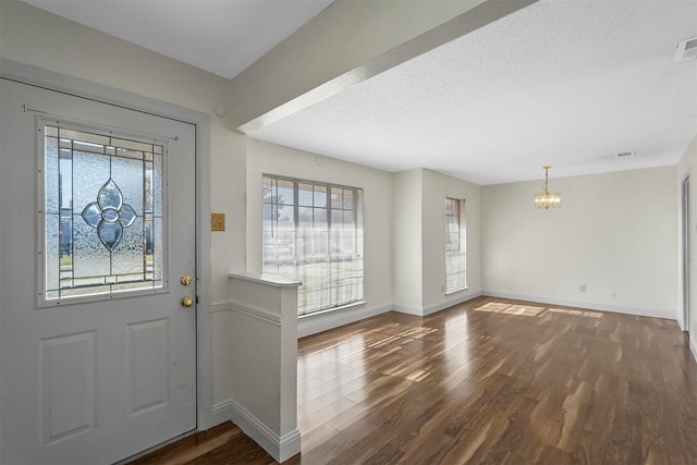 entryway with a textured ceiling, dark hardwood / wood-style flooring, and a notable chandelier