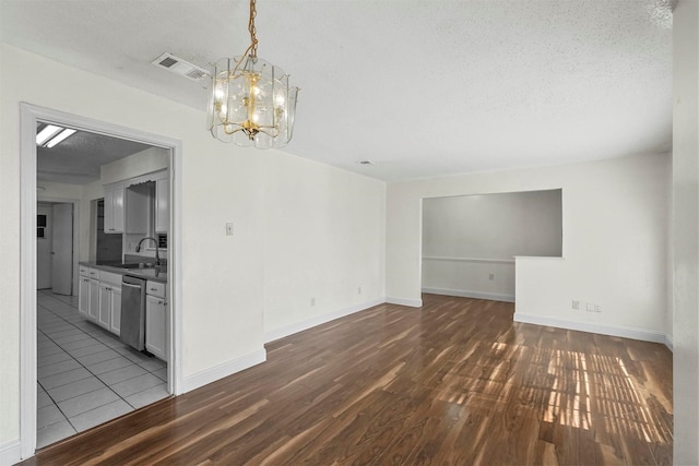 unfurnished room featuring sink, dark wood-type flooring, a textured ceiling, and a notable chandelier