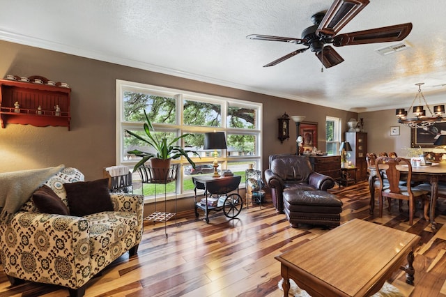 living room with ceiling fan with notable chandelier, hardwood / wood-style flooring, a textured ceiling, and visible vents