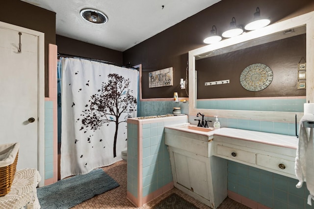 full bath featuring tile patterned flooring, vanity, tile walls, a shower with shower curtain, and a wainscoted wall