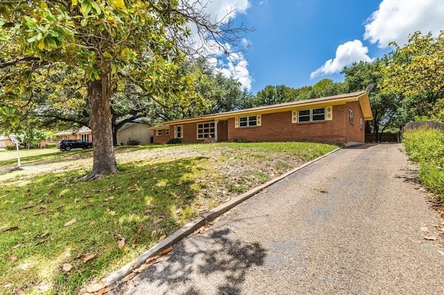 ranch-style house with brick siding, driveway, fence, and a front yard