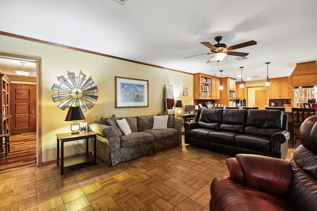 living area featuring baseboards, ornamental molding, a ceiling fan, and visible vents