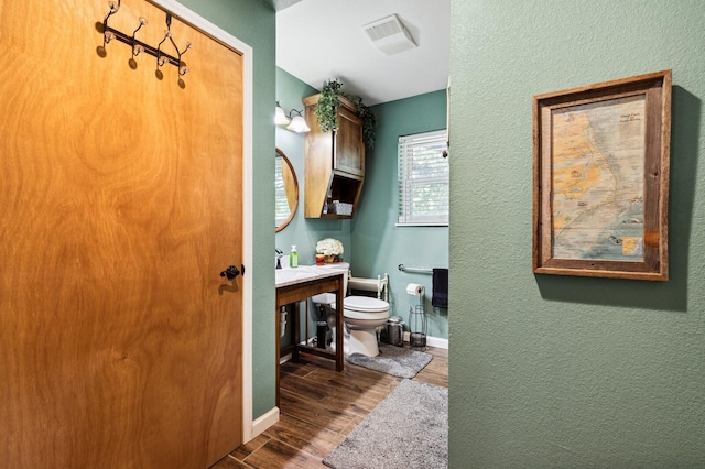 bathroom with toilet, baseboards, visible vents, and wood finished floors