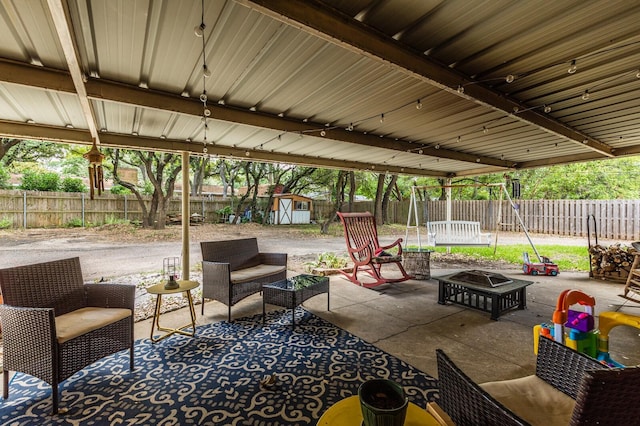 view of patio with an outdoor living space with a fire pit, an outbuilding, a fenced backyard, and a storage unit