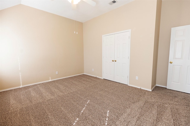 unfurnished bedroom with vaulted ceiling, carpet flooring, a closet, and ceiling fan