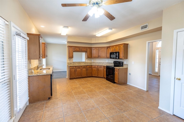 kitchen featuring light stone countertops, black appliances, light tile patterned flooring, and ceiling fan