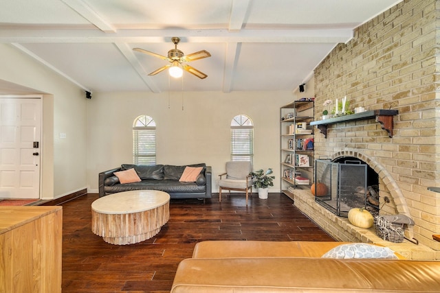 living room featuring ceiling fan, dark hardwood / wood-style flooring, beamed ceiling, and a brick fireplace