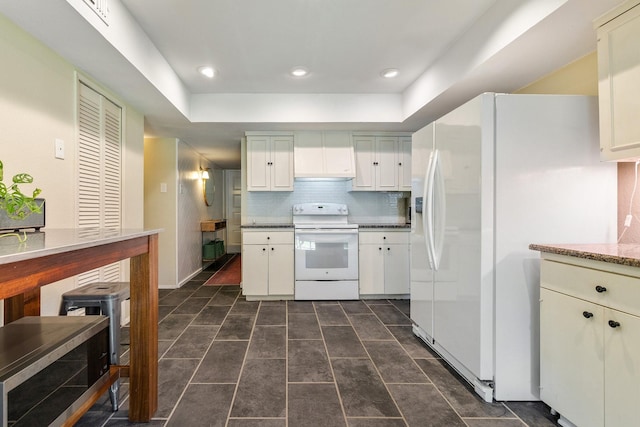 kitchen featuring white appliances, premium range hood, a tray ceiling, and tasteful backsplash