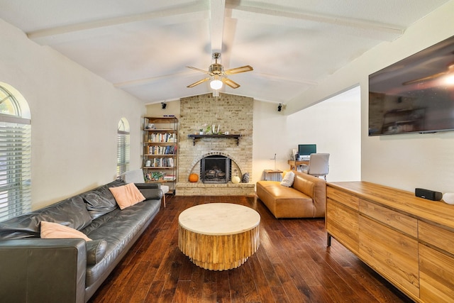 living room with vaulted ceiling with beams, ceiling fan, dark hardwood / wood-style floors, and a brick fireplace