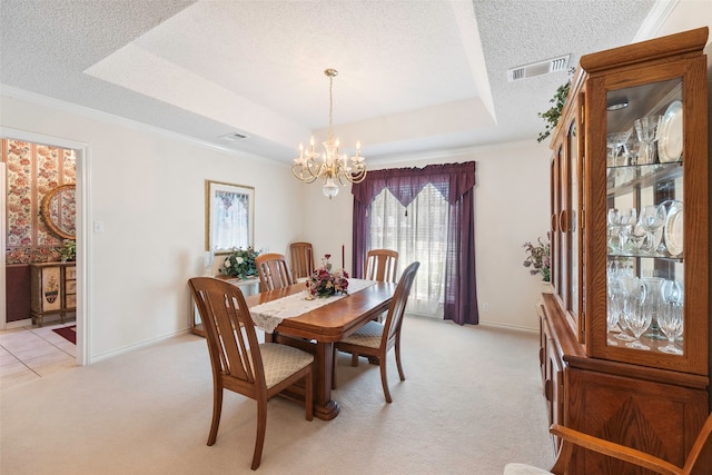 carpeted dining area featuring crown molding, a textured ceiling, a chandelier, and a tray ceiling