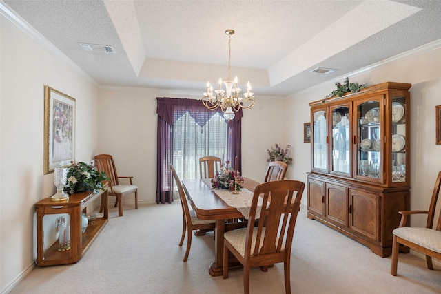 carpeted dining room featuring ornamental molding, a textured ceiling, a chandelier, and a tray ceiling